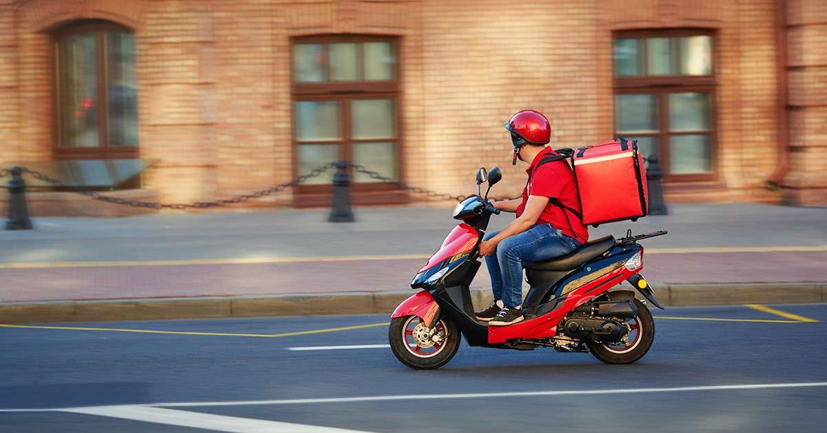 man riding motorbike with food delivery bag on back