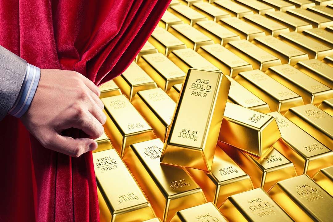 Hand opening curtain to reveal gold bullion